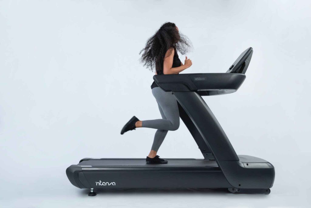 Woman running on an Intenza 450 i2S treadmill against a clean studio background.