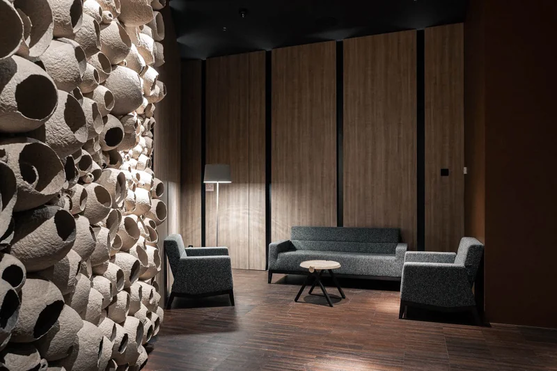 Modern lounge area in hotel lobby with sculptural wall installation and minimalist seating